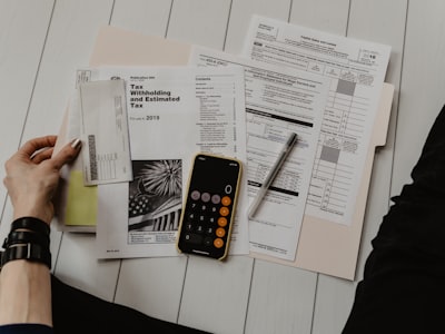 Hand filling out tax and payment paperwork with a calculator